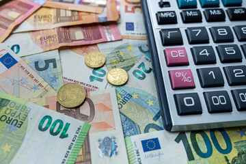 Obraz na płótnie Canvas Euro coin and calculator above euro bills. Saving and finance concept