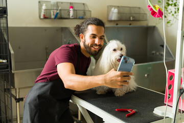 Smiling man and pet groomer taking a selfie with a dog