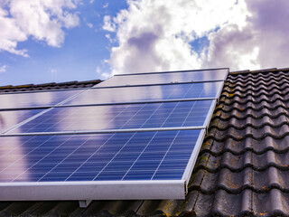 PV system with solar panels on a house roof with moss and lichen on the tiles
