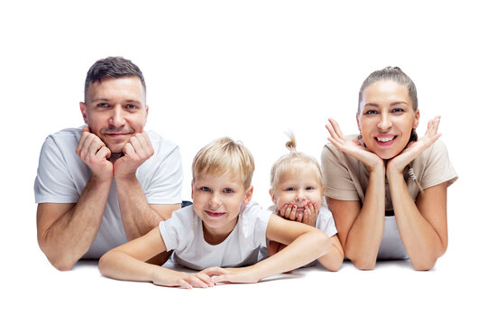 Smiling family with two small children lie on the floor isolated on white. Mom, dad and little son and daughter. Love and tenderness.