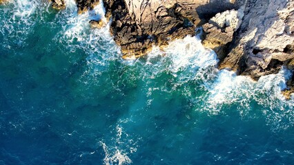 The captivating drone photo as powerful waves crash against rugged rocks Aerial photo of the sheer force of the waves colliding with the stone A mesmerizing display of splashing water