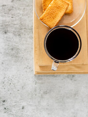 Top shot of black coffee with rusk placed on books.