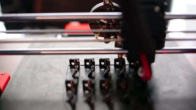 3D printer working assembling a black plastic object at the factory