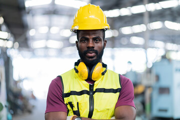 Portrait of smiling African American industrial worker man with helmet crossed arms in industry...