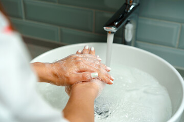 Close up of a woman washing her hands in a bathroom sink