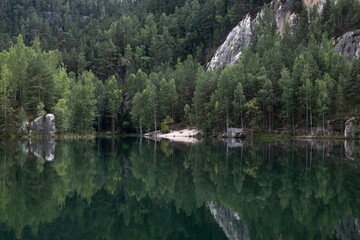 Fototapeta na wymiar Forest with rock reflecting in Lake water surface. Nature in Europe