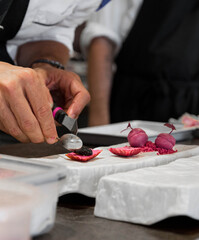 Vertical photo of a chef's hands finishing a dish with caviar in a gastronomic restaurant.