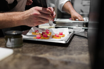 Photo of the hands of a chef finishing some dishes in a gastronomic restaurant.