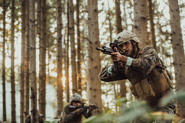 A group of modern warfare soldiers is fighting a war in dangerous remote forest areas. A group of soldiers is fighting on the enemy line with modern weapons. The concept of warfare and military