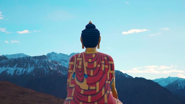 Rear view shot of Langza Buddha statue in front of the Snow covered Himalayan mountains at Langza village in Spiti Valley, Himachal Pradesh, India. Statue of Buddha facing the snowy Himalayas in India