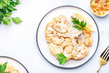 Vegan steak from baked cauliflower with garlic butter, parley and spice on plate, white table background, top view