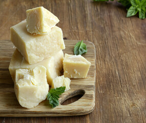 hard parmesan cheese block on wooden board