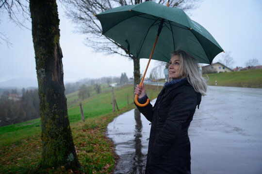 Germany, Sonthofen, Smiling woman with umbrella in rural landscape
