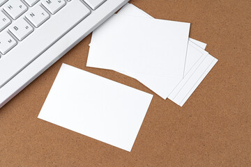 Blank business cards with supplies and keyboard on office table.