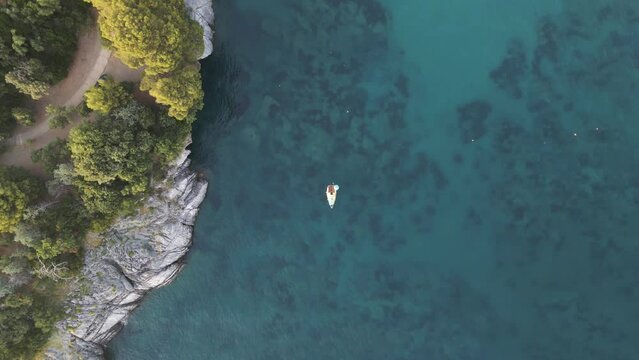 Aerial view of a sailing boat moored along the cliffs in the Mediterranean Sea at sunset, Maratea, Potenza, Italy.