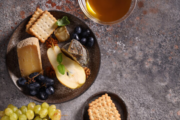 cheese on a wooden board with grapes and honey