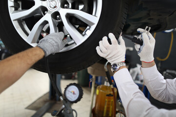 Vehicle inspection Auto technician repairs car tire at service station. Correct tire pressure