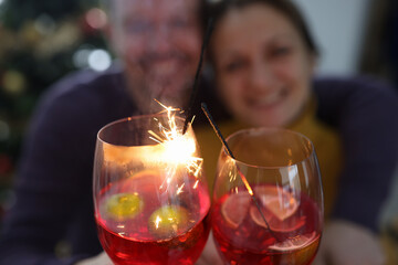 Valentine Day New Year Christmas concept. Background of happy smiling cheerful attractive couple celebrating with glasses of champagne or cocktail and sparklers