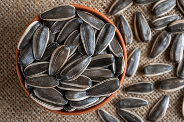 Black sunflower seeds in a bowl on burlap sack