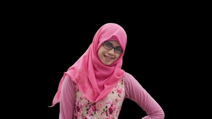Close up portrait of young Muslim woman wearing pink hijab and dress with red rose motif and eyeglasses. Smiling and happy expression.