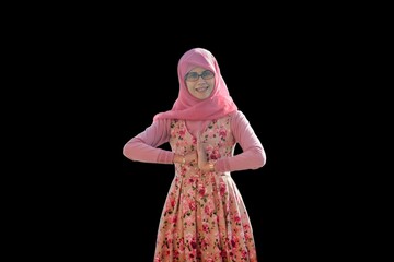Close up portrait of smiling young Muslim woman wearing pink hijab and dress with flower motif hands and arms making Chinese salutations or greetings gesture. Happy and cheerful expression.