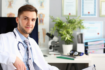 Smiling male general practitioner looking at camera in clinic. Professional medical worker in...