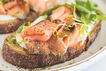 Breakfast toast with cream cheese, salmon, oil and arugula, white background. Keto diet recipe.