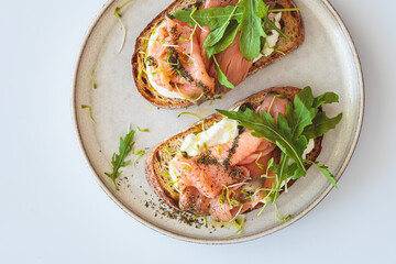 Fototapeta na wymiar Breakfast toast with cream cheese, salmon, oil and arugula, white background. Keto diet recipe.