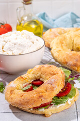 Cottage cheese bagel sandwich. Healthy keto diet high-protein and vegetable breakfast or snack, with curd cheese bagels bread, cottage cheese spread and fresh veggies