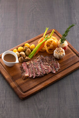 Grilled rib eye steak with pepper sauce on wooden background