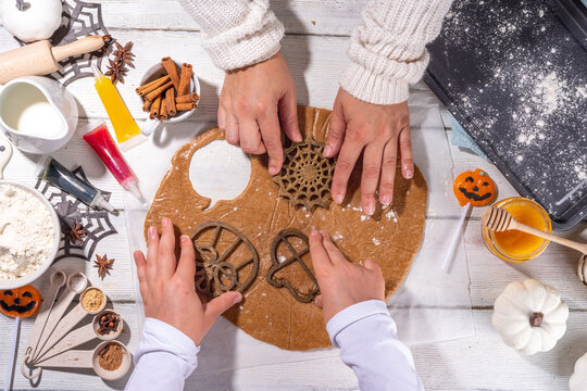 Cooking baking Halloween gingerbread cookies. Preparing for Halloween party holiday, mom and child cook together, make cut homemade funny cookies with molds in form of holiday symbols and monsters 