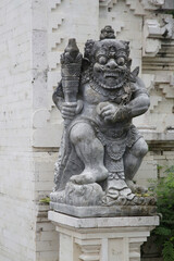 Fototapeta na wymiar Balinese white sandstone statue in front of temple