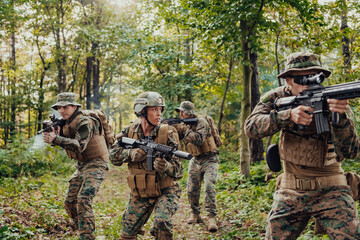 Fototapeta premium A group of modern warfare soldiers is fighting a war in dangerous remote forest areas. A group of soldiers is fighting on the enemy line with modern weapons. The concept of warfare and military