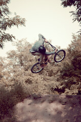 Naklejka premium Young sportive man riding bmx bike outdoors, training, doing difficult and dangerous tricks with sport bike. Concept of active lifestyle, sport, extreme, dynamics, hobby, freestyle