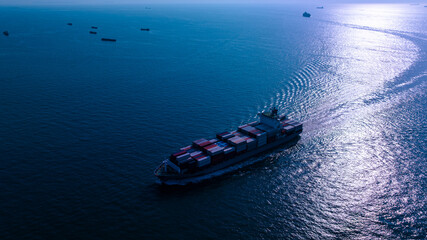night process blue tone of cargo container ship sailing full speed in sea to import export goods and distributing products to dealer and consumers worldwide, by container ship Transport business