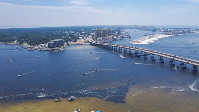 Downtown Destin Florida with Destin Bridge or William T. Marler Bridge connect Santa Rosa Island beach near Crab Island with busy speeding boats on turquoise water along Gulf of Mexico