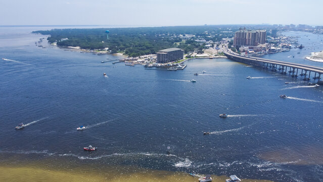 Downtown Destin Florida with Destin Bridge or William T. Marler Bridge connect Santa Rosa Island beach near Crab Island with busy speeding boats on turquoise water along Gulf of Mexico