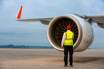 Controlling the jet engine of a modern commercial airplane. Technical service employee checking the jet engine of a parked passenger plane at the airport. - obrazy, fototapety, plakaty