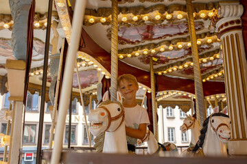 Children, boys, going on Merry Go Round, kids play on carousel in the summer