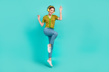 Full size portrait of pretty crazy girl jumping listen new hit single isolated on turquoise color background