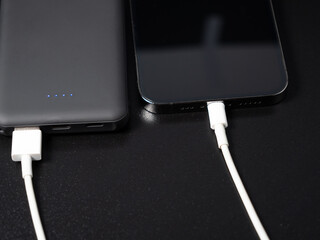 Power bank for charging mobile devices on a black background. Smartphone charger with power supply....