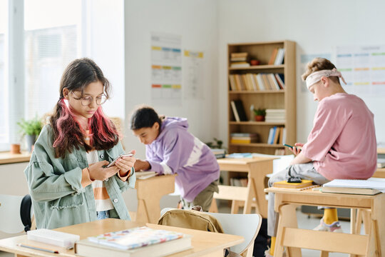 Group of school children using smartphones at break in the classroom