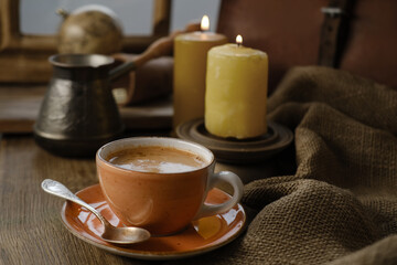 cup with drink coffee on old vintage wooden table, metal coffee maker, candles burn, caffeine...