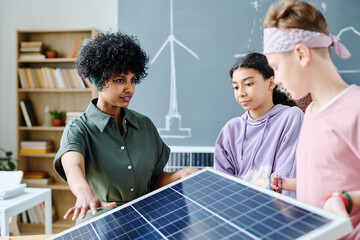 Teacher showing solar panel to students during lesson in classroom