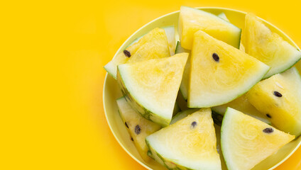 Yellow watermelon slices on yellow background.