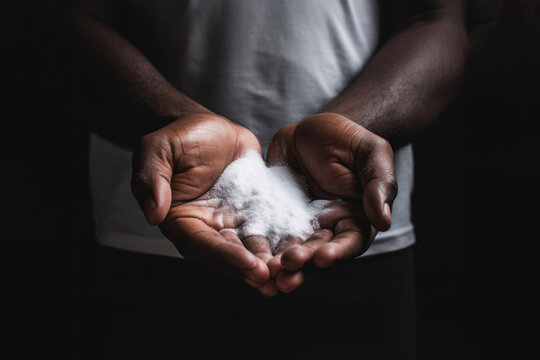Closeup man hands holding white salt on dark background. Manufacturing concept