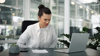Female freelance manger businesswoman in formal outfit sits on a chair in the office and suffers from abdominal pain. A woman with menstrual pain or poisoning, suffers from abdominal cramps.