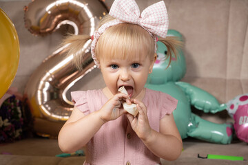 A two-year-old girl inflates a balloon on her birthday.