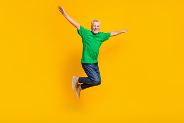 Fototapeta na wymiar Full size portrait of active cheerful aged person jumping raise arms wings flying isolated on yellow color background