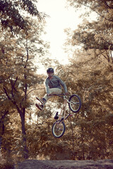 Young man riding on bike training in the park, doing tricks in the air on a BMX bike. Training activity. Jumping. Concept of active lifestyle, sport, extreme, dynamics, hobby, freestyle